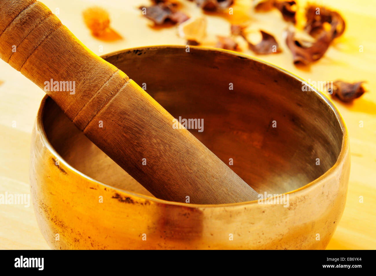 Nahaufnahme von einer tibetischen Klangschale mit seinen Hammer auf einem Tisch mit Trockenblumen Stockfoto