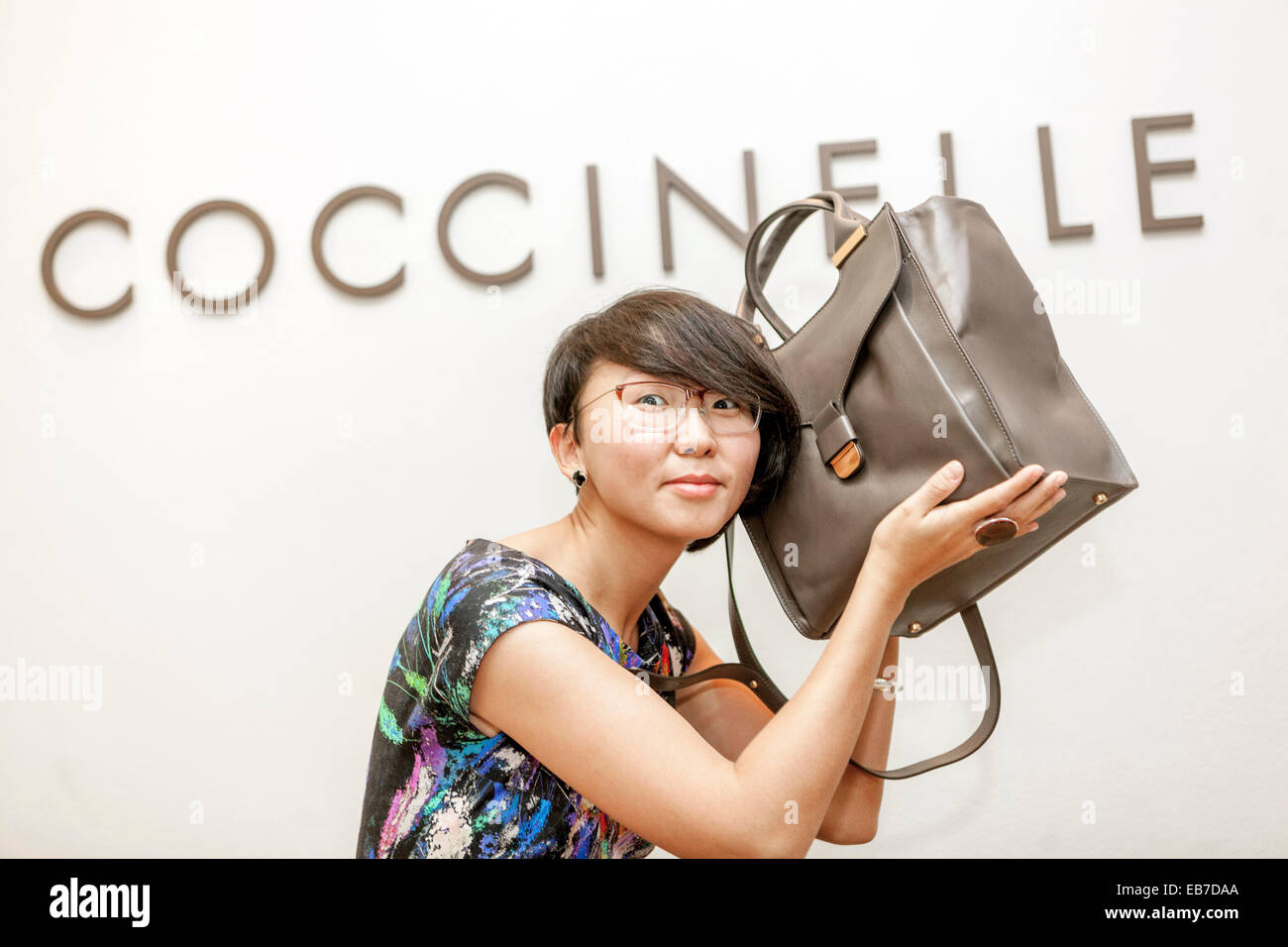 Junge Asiatin mit einer Handtasche Coccinelle Stockfoto