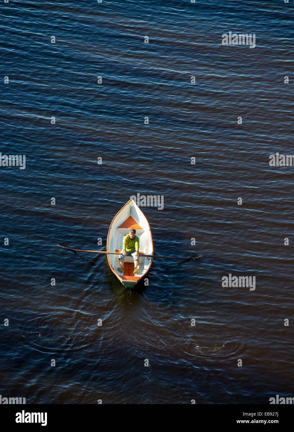 Luftaufnahme eines älteren Mannes, der ein kleines Fiberglas-Ruderboot / Skiff / Schlauchboot in Finnland rudert Stockfoto