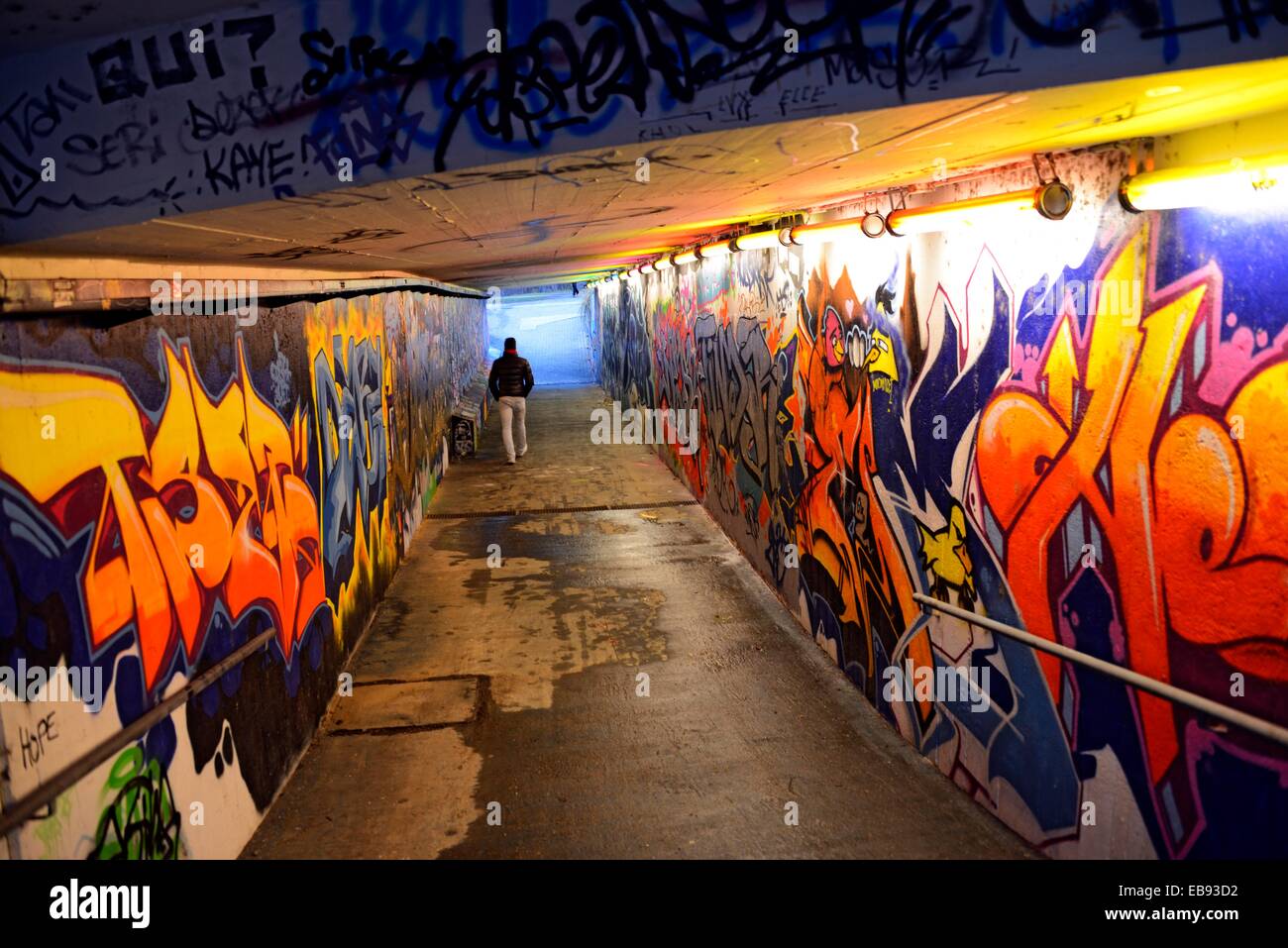 Tunnel - Durchgang unter der Straße Wände bedeckt mit bunten Graffiti zeitgenössische Stadt Szene junger Mann zu Fuß Lebensstil Stockfoto