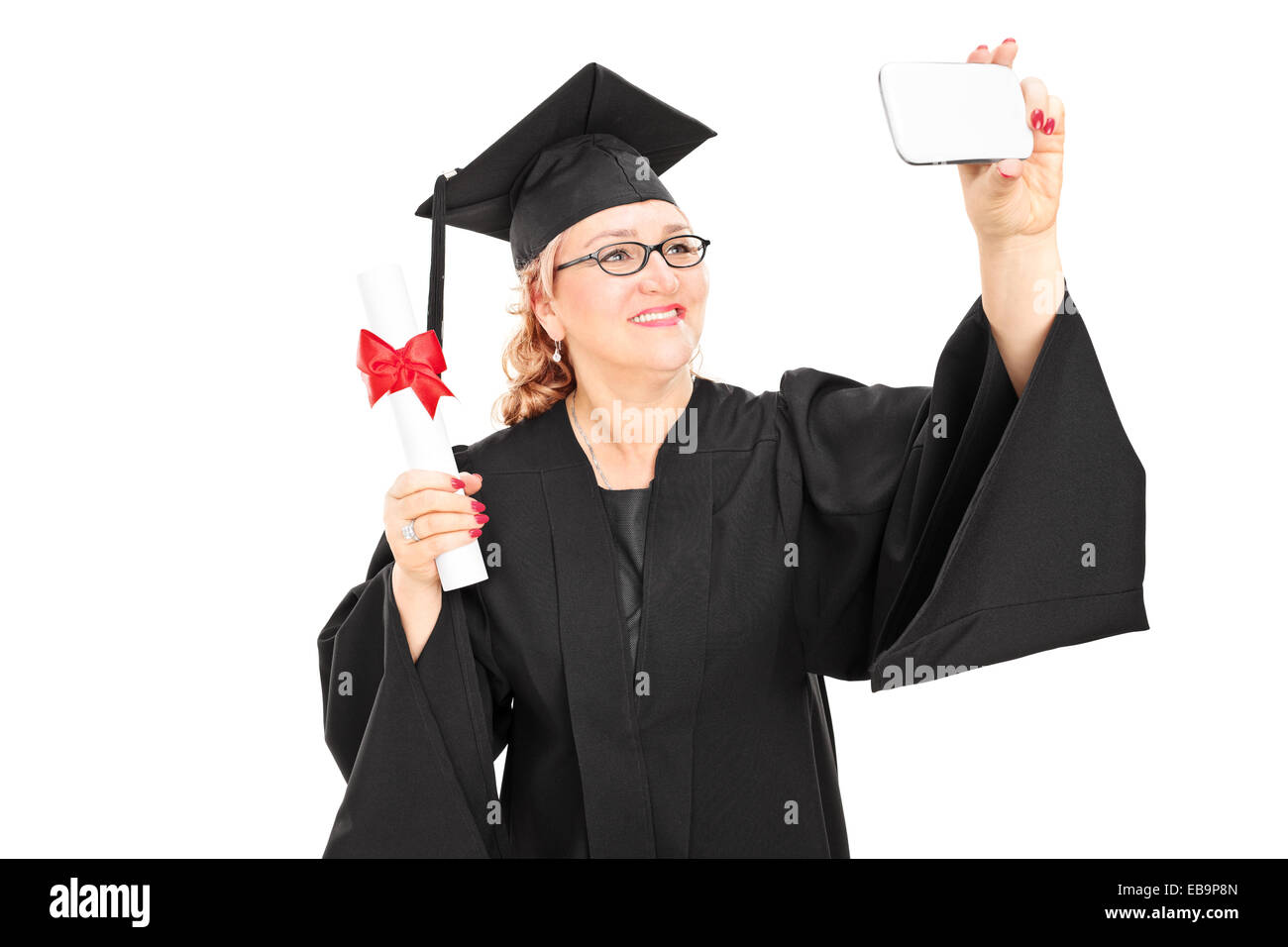 Reife weibliche Absolventin unter ein Selbstporträt mit Handy isoliert auf weißem Hintergrund Stockfoto
