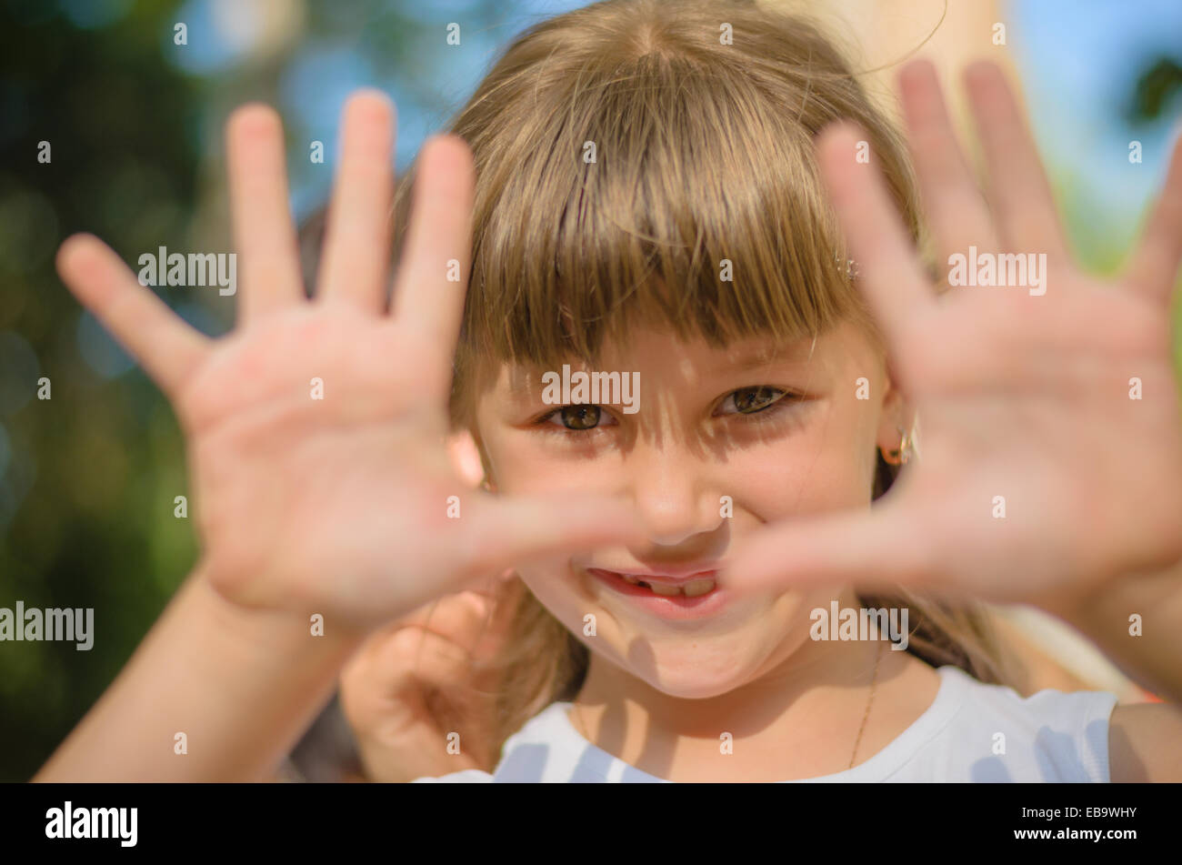 Lächelndes Mädchen zeigt ihre Hände bilden einen Rahmen Stockfoto