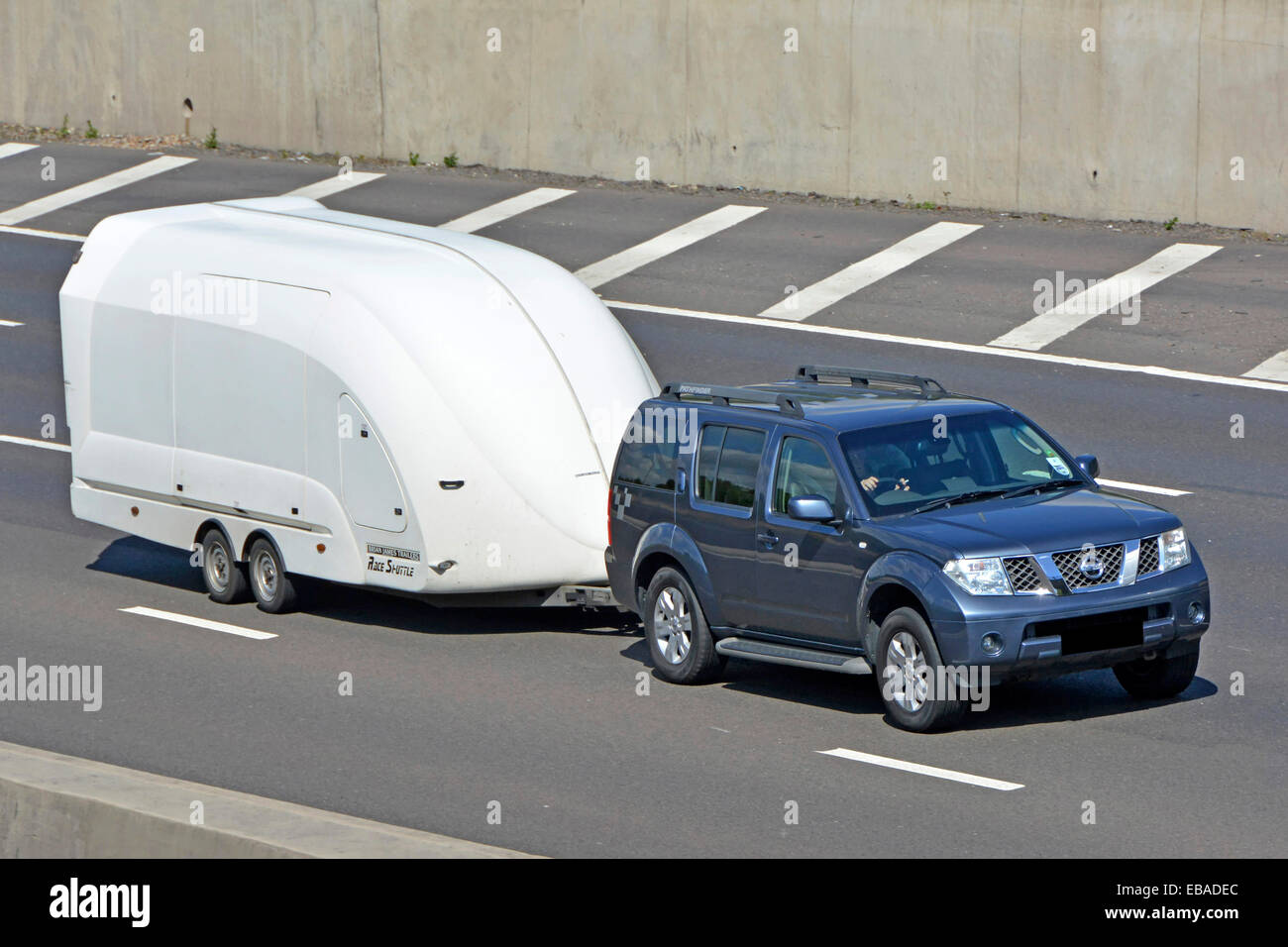 Nissan-Auto in Bewegung schleppt ein geschlossenes geheimes Auto, das Anhänger auf der Londoner Autobahn Orbital M25 in Essex England, Großbritannien, transportiert Stockfoto