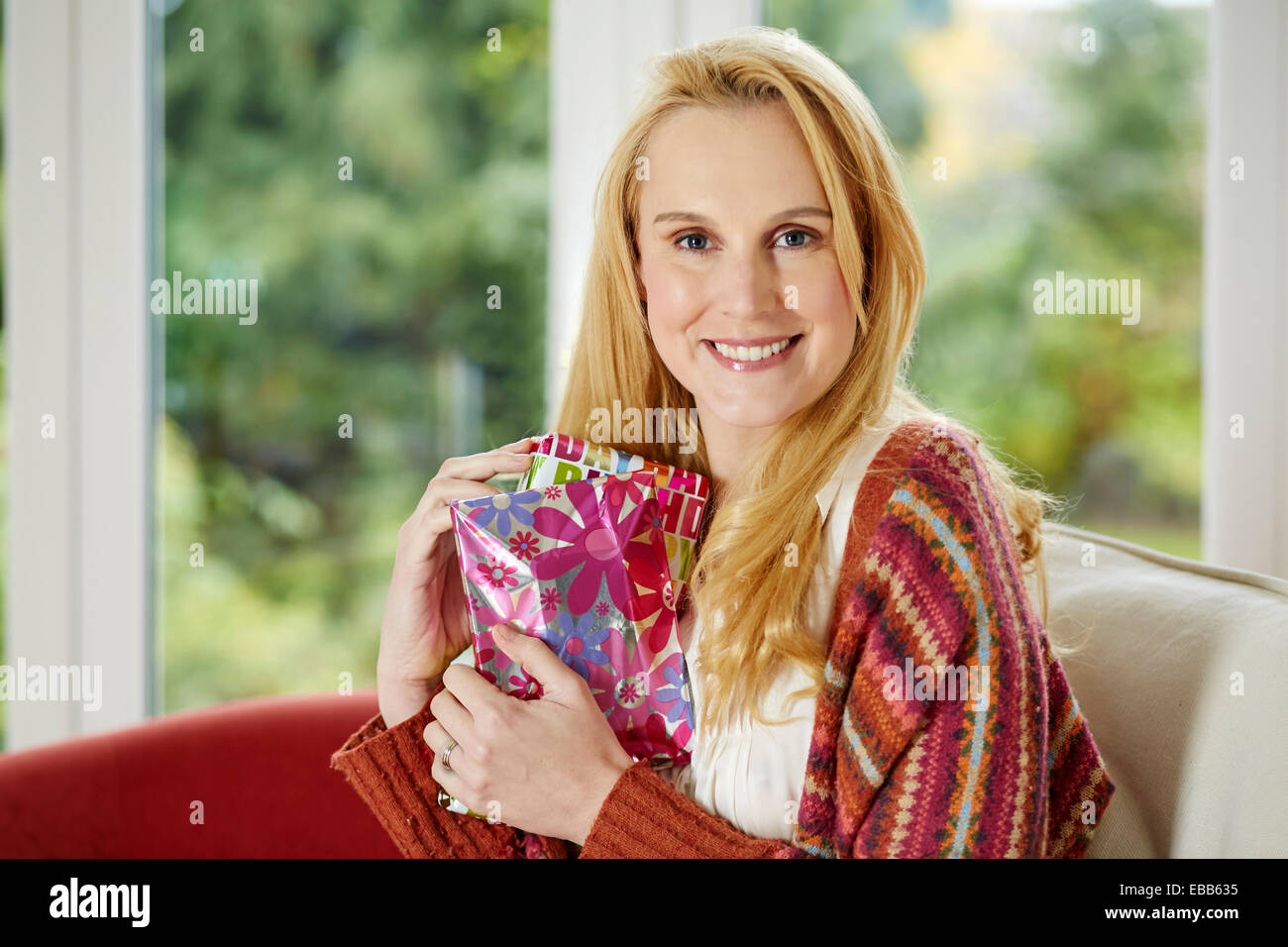 Glückliche Frau saß mit Geburtstag präsentiert Stockfoto