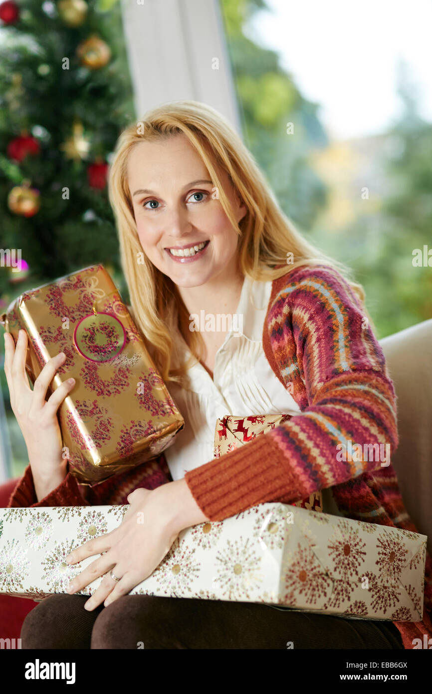 Glückliche Frau saß mit Weihnachten präsentiert Stockfoto