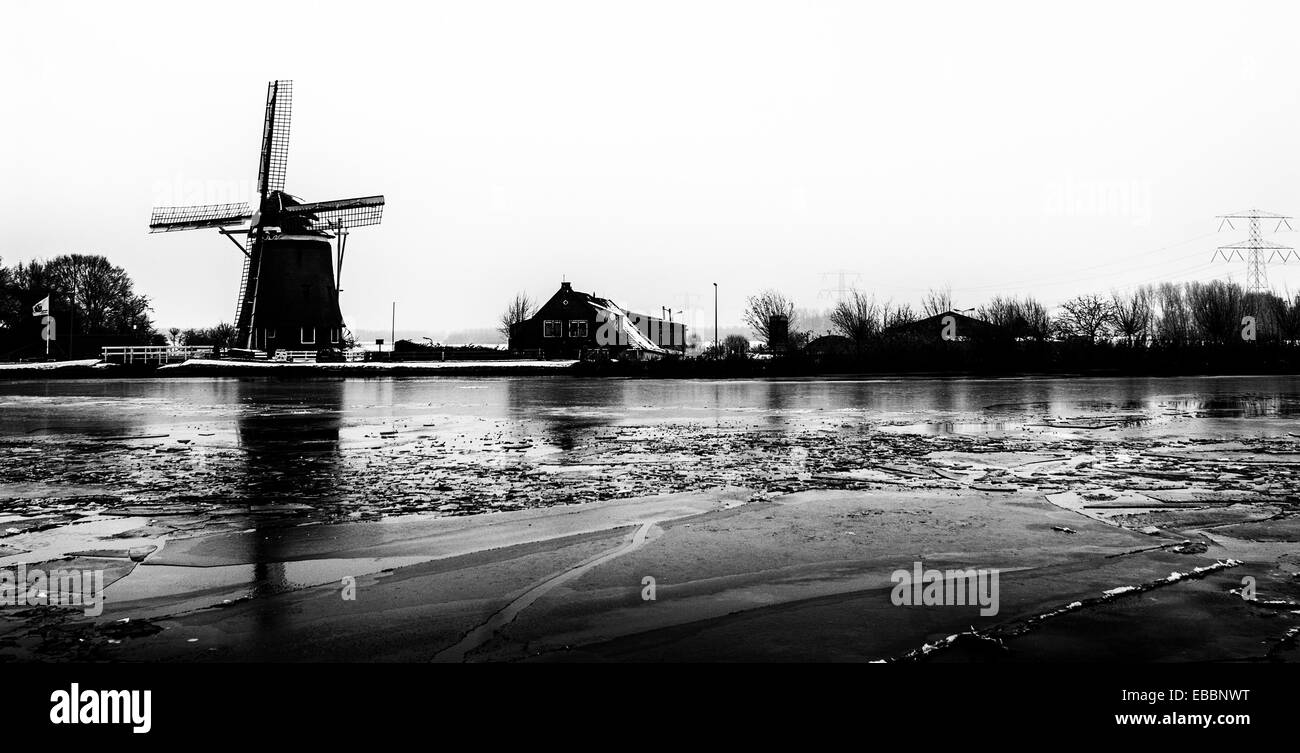 Holländische Windmühle in malerischen Winterlandschaft mit gefrorenen Kanal im B&W Stockfoto