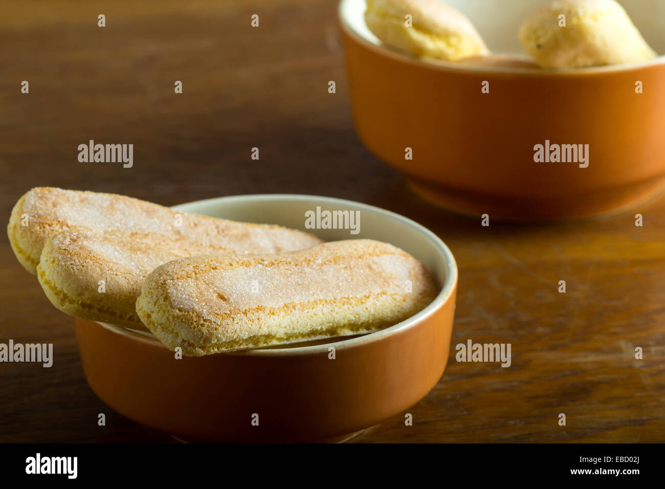 Frische Löffelbiskuits in Schüssel auf Holztisch Stockfoto
