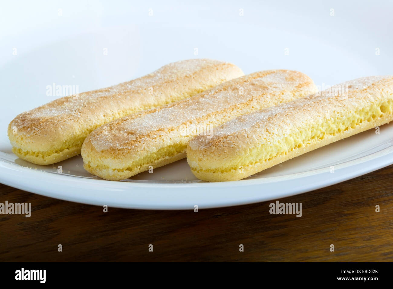 Frische Löffelbiskuits auf dem Teller auf Holztisch Stockfoto