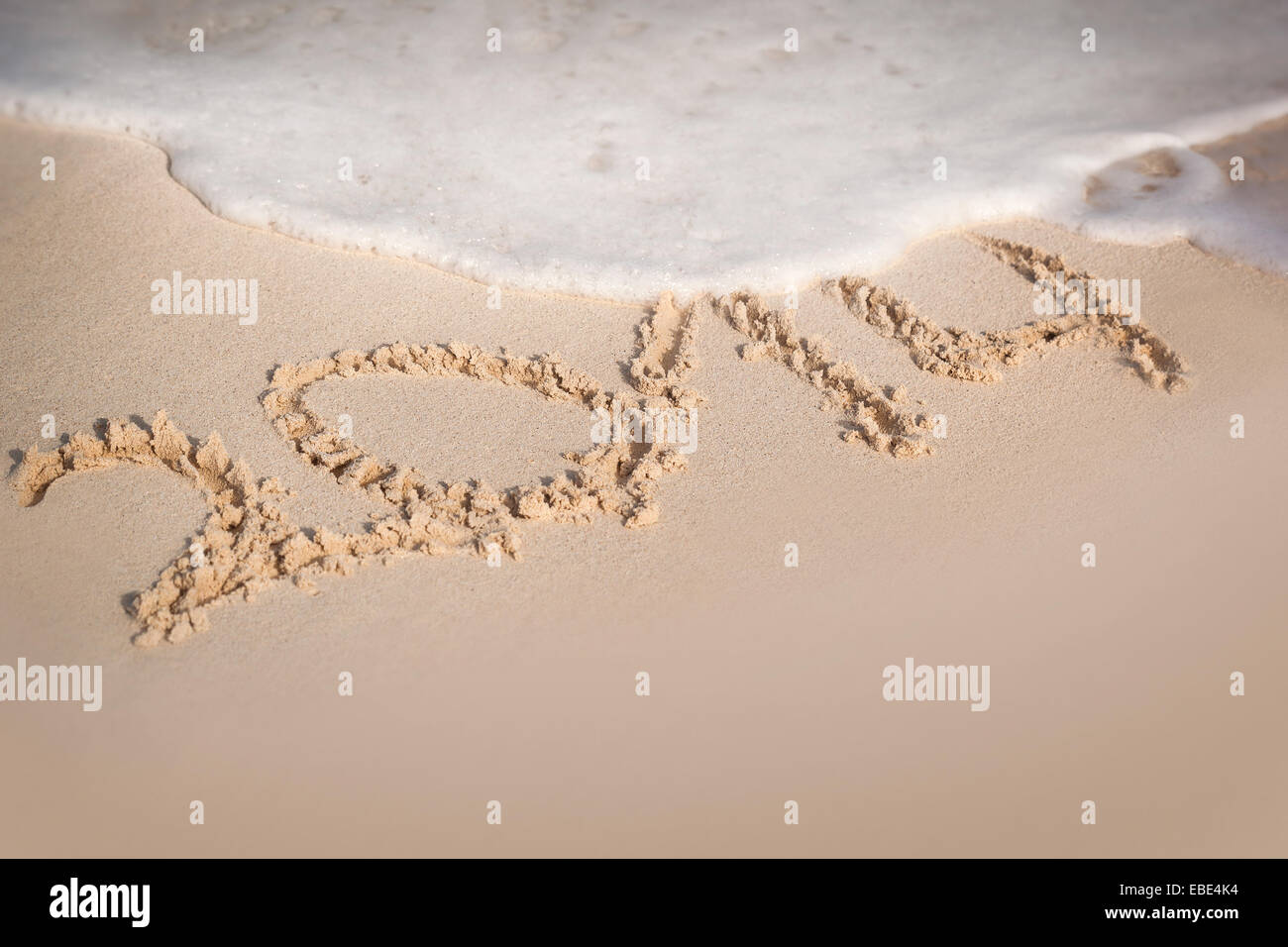 Inschrift 2014 am Sandstrand mit Wave-Schaum, kostenloses Exemplar Stockfoto