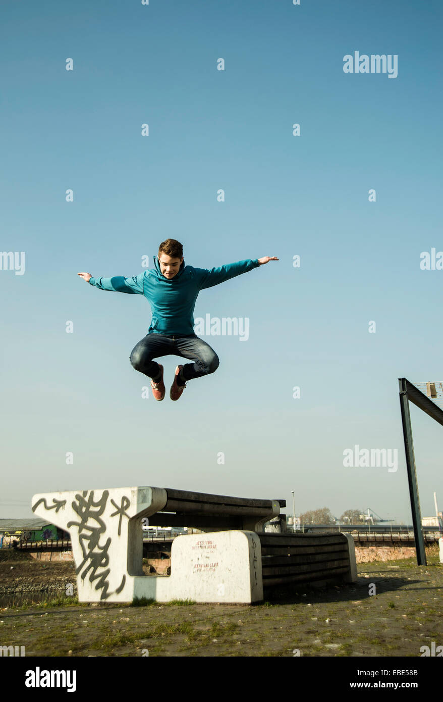 Teenager-Jungen springen über Bank im Freien, Industrail Area, Mannheim, Deutschland Stockfoto