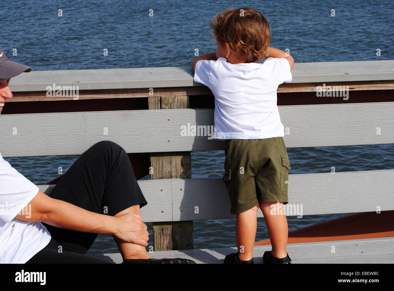 Mutter ihres Sohnes zu beobachten, wie er auf die Bucht Gewässer neben dem Fishing Pier blickt. Stockfoto