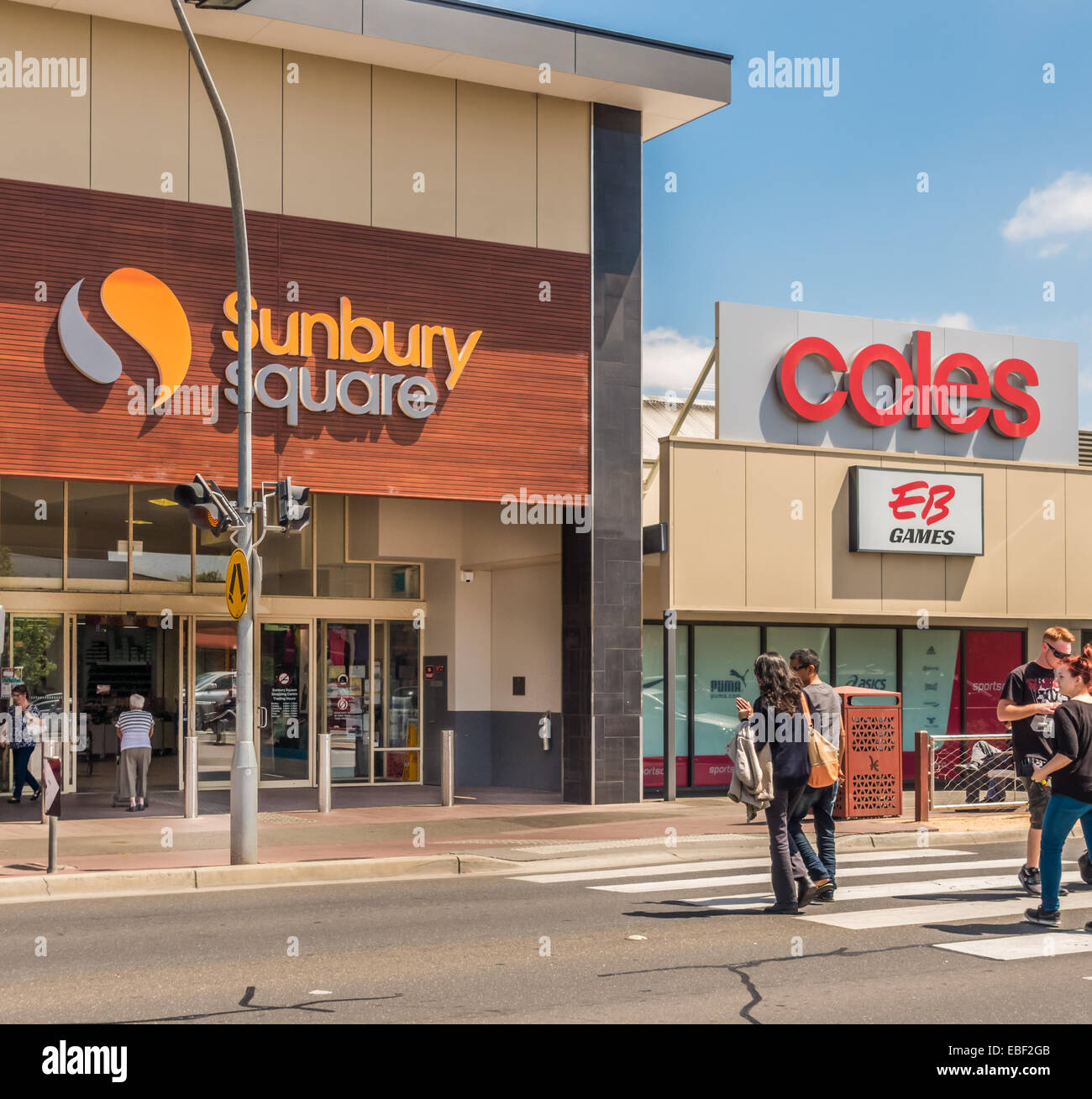 Menschen Kreuzung Straße unter Coles und EB speichern Zeichen in Sunbury, Victoria, Australien Stockfoto