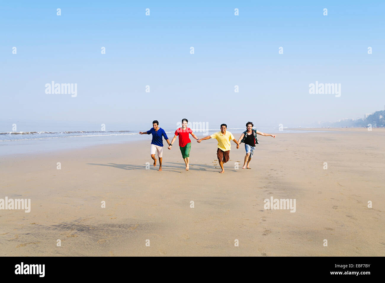 indische Freunde am Strand laufen Stockfoto