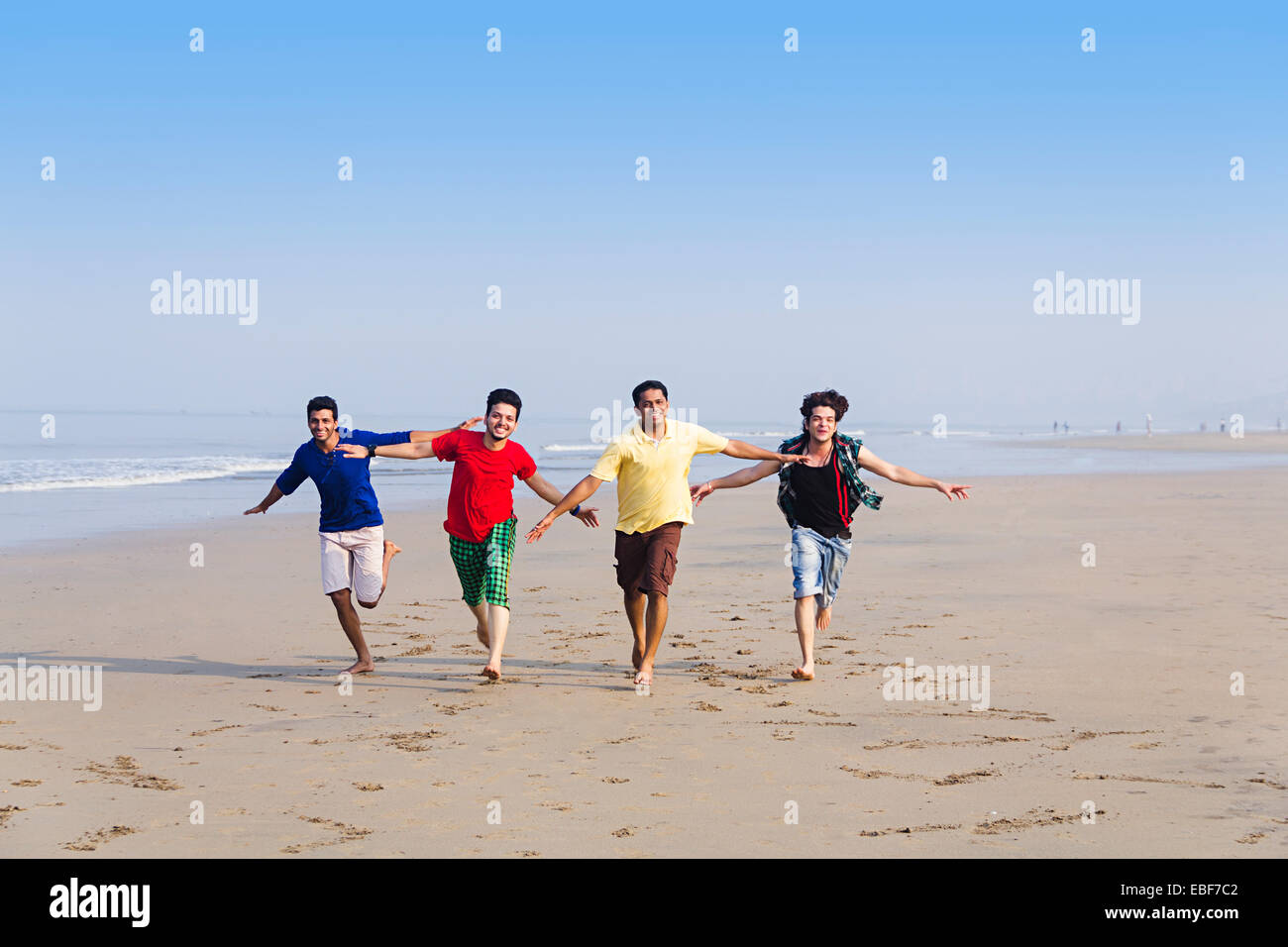 indische Freunde am Strand laufen Stockfoto