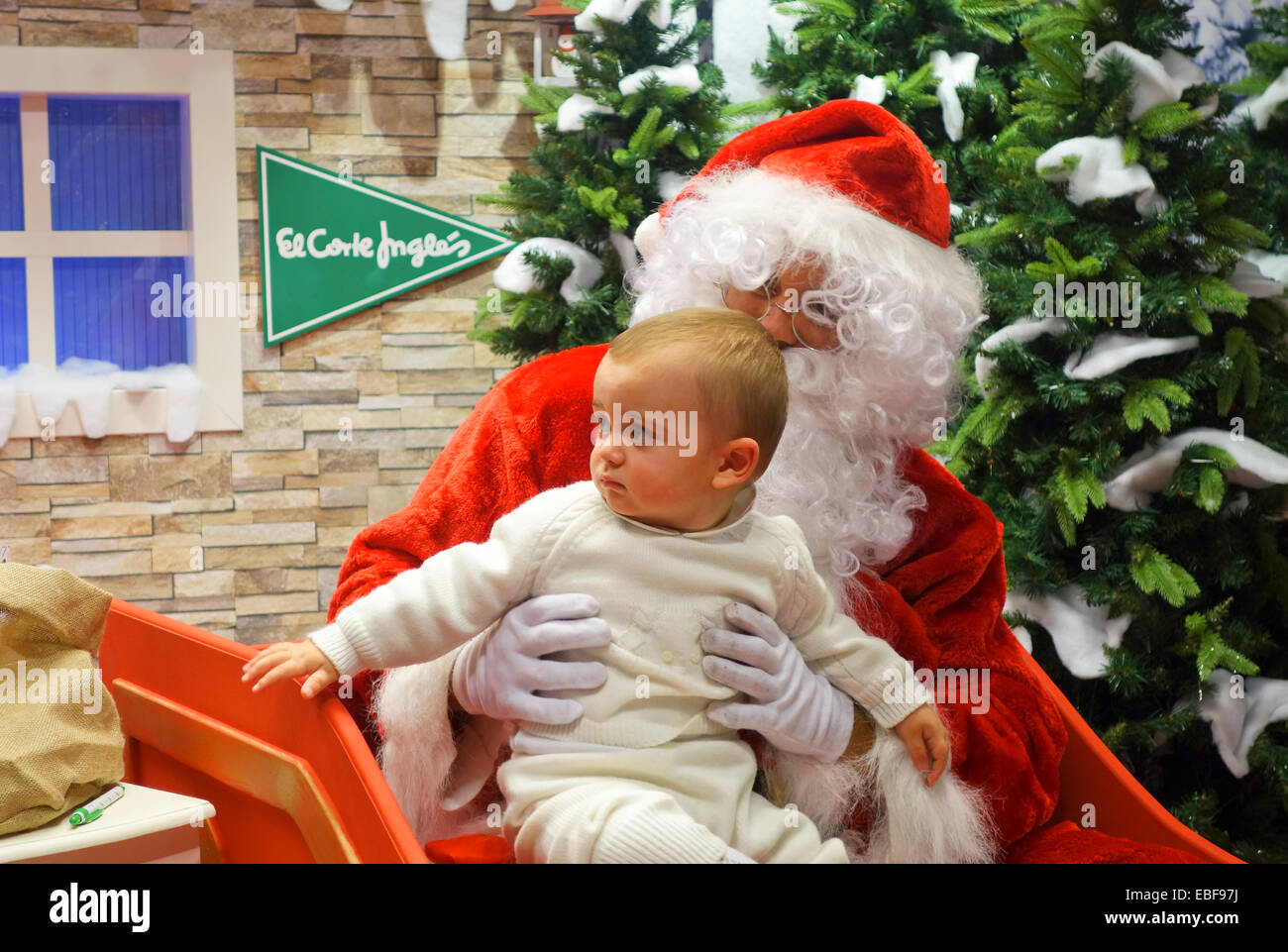 Weihnachtsmann am Einkaufszentrum mit Baby auf dem Schoß. El Corte Ingles, Spanien Stockfoto