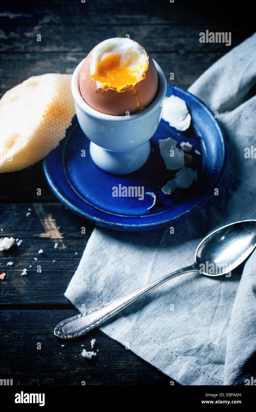Frühstück mit weich gekochtes Ei, serviert mit Brot über alten Holztisch. Stockfoto