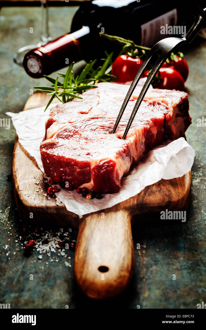 Marmorierte Rindfleischsteak mit einer Flasche Wein und Gemüse auf alten Holz Hintergrund Stockfoto
