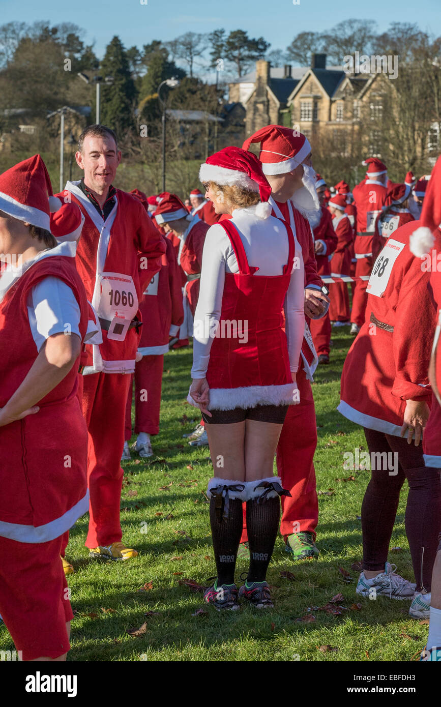 Menschen (Männer, Frauen und Kinder) Gekleidet in rot & weiß Vater Weihnachten Outfits mit Hüte & falsche Bärte, Stehen, warten Teil in der Großen Skipton Santa Fun Run, eine jährliche fundraising Charity Rennen vom Rotary Club - Aireville Park, Skipton Stadtzentrum, dem North Yorkshire, England, UK organisiert wird. Stockfoto