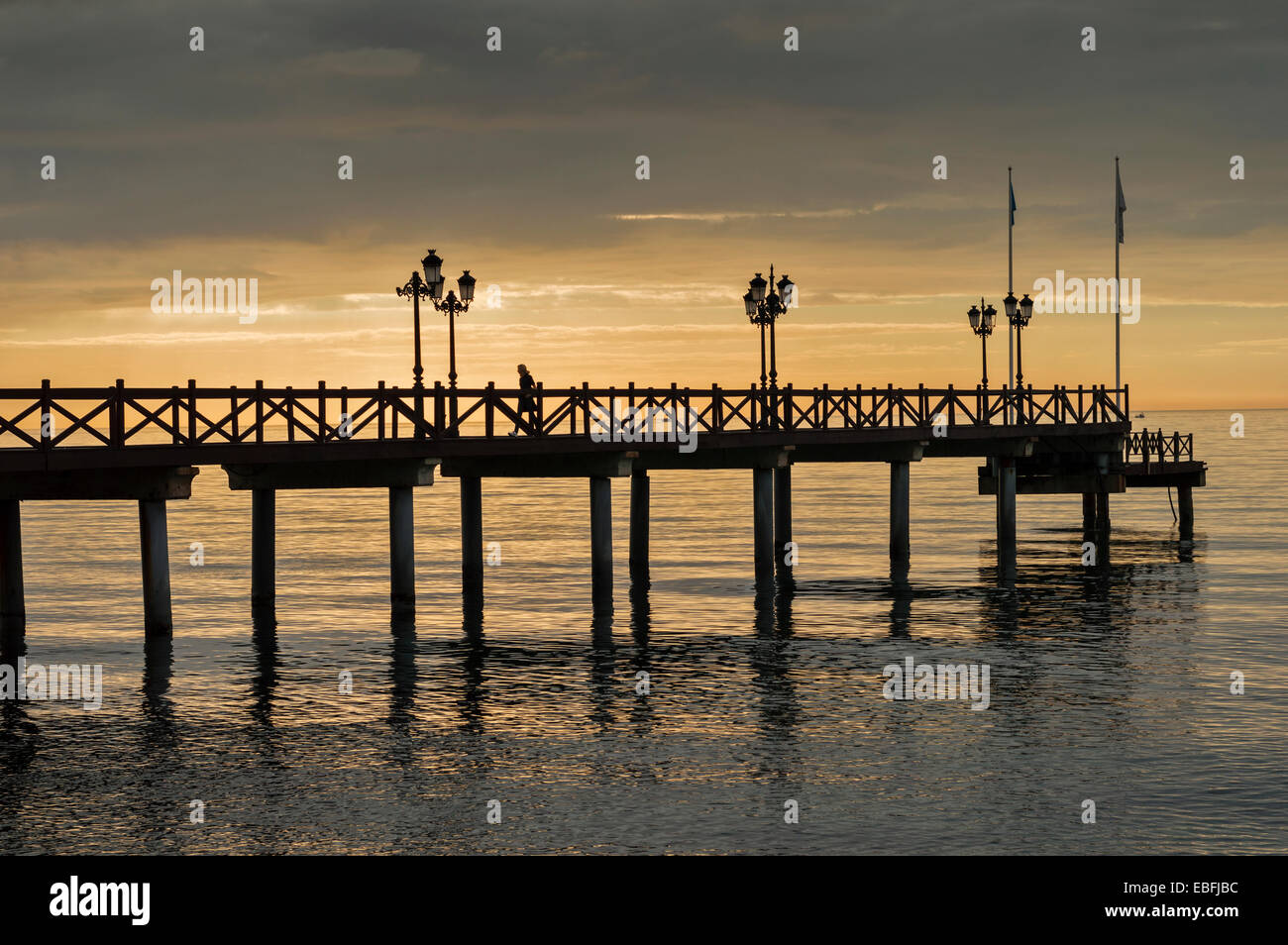 SONNENAUFGANG ÜBER EINEM RUHIGEN MEER UND PIER Stockfoto