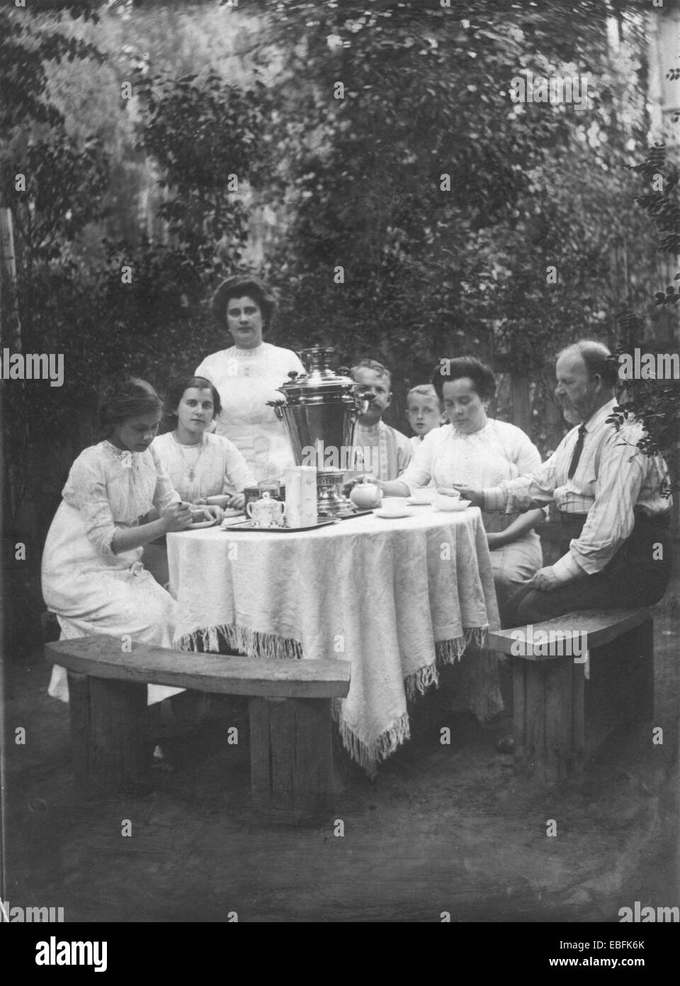 Tee im Garten. Familie, sitzen an einem runden Tisch mit einem Samowar. Retro-Fotografie, Russland, ca. 1905 Stockfoto
