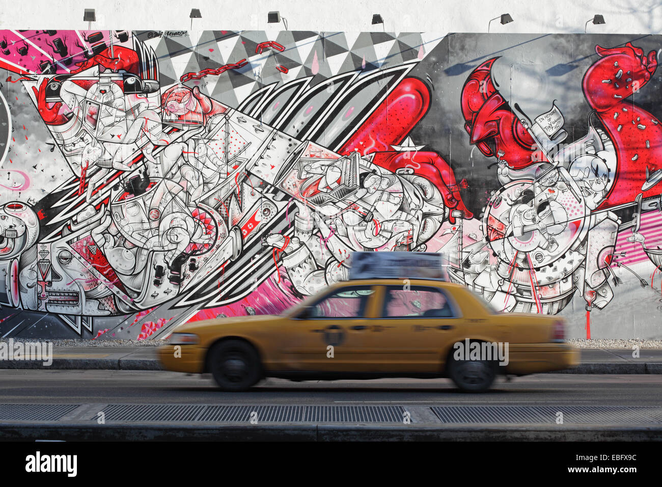 Gelbes Taxi Geschwindigkeiten vorbei an einem bunten Wandgemälde an der Bowery Wandbild Wand auf der Houston Street, Lower East Side von Manhattan Stockfoto