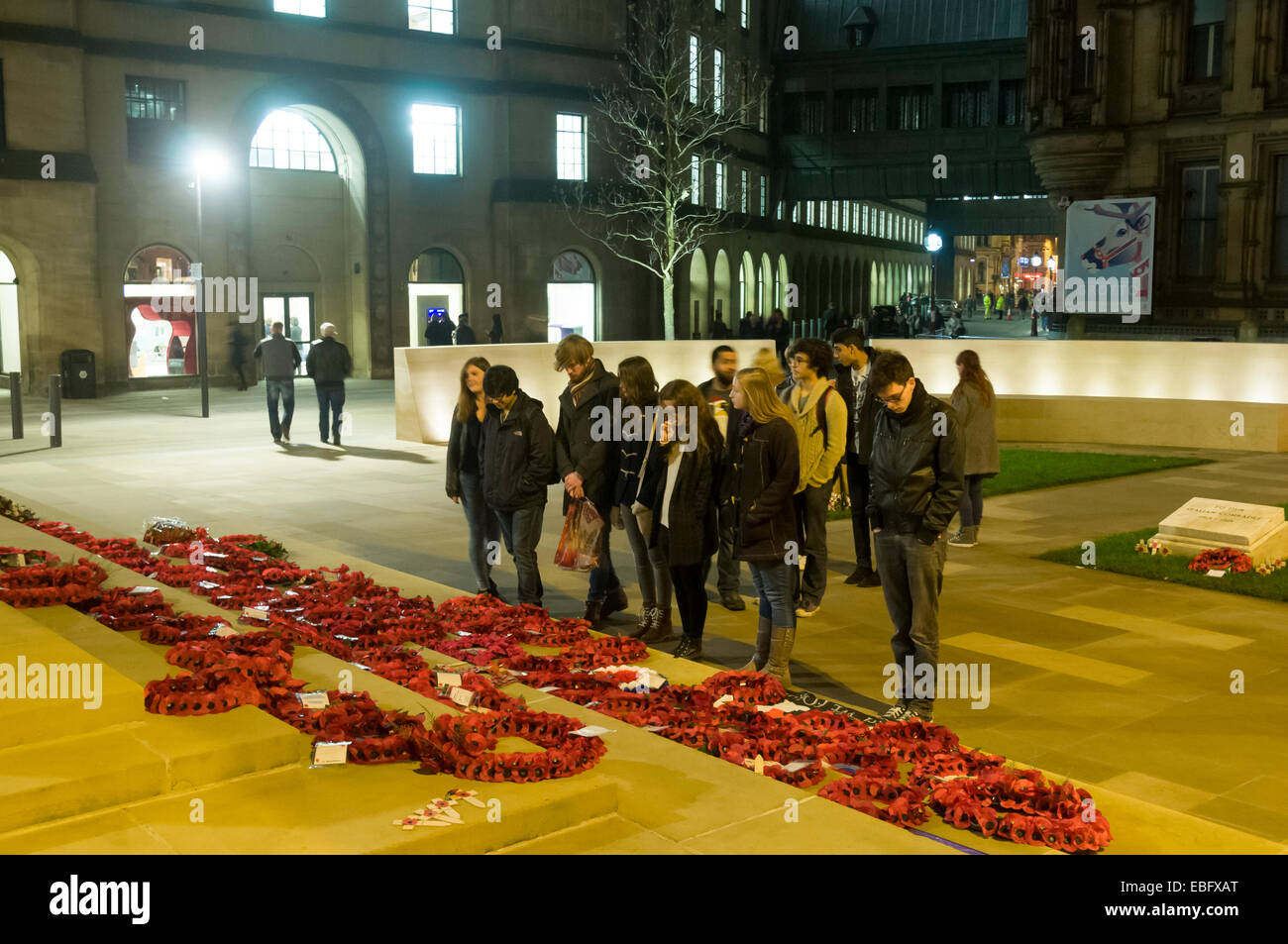 Gruppe junger Leute betrachten den Gedenktag Mohn Kränze am Ehrenmal, Petersplatz, Manchester, England, UK Stockfoto