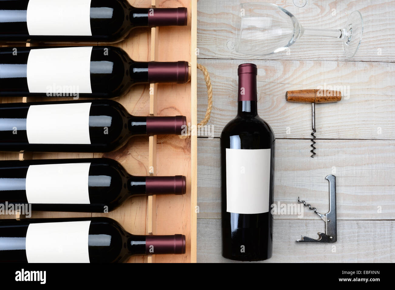 Hohen Winkel Schuss des Schrankes roten Wein in Flaschen mit leeren Etiketten neben einer einzigen Flasche ein Weinglas und Korkenzieher auf einem rustikalen Stockfoto