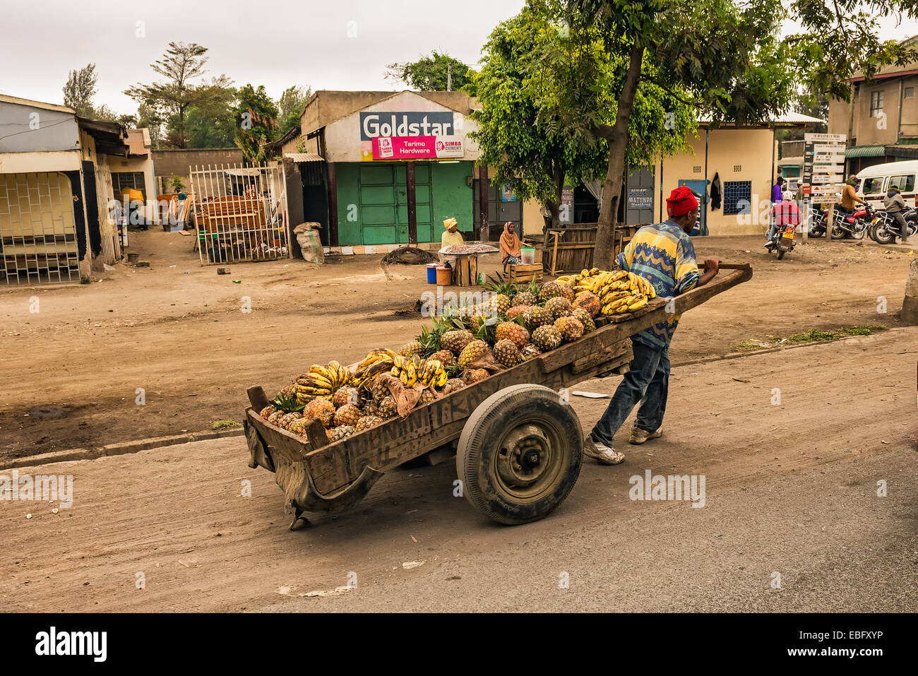 Afrikanischer Mann ziehen einen Karren voller Früchte in einer Einkaufsstraße von Arusha Stockfoto