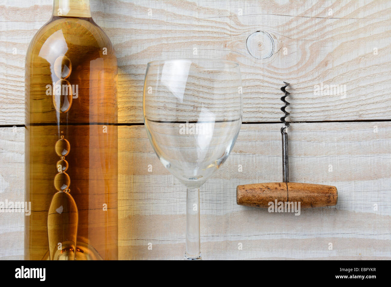 Hohen Winkel Nahaufnahme einer Flasche Weißwein neben einem Weinglas und Korkenzieher auf einem weiß getünchten rustikalen Tisch. Querformat. Stockfoto