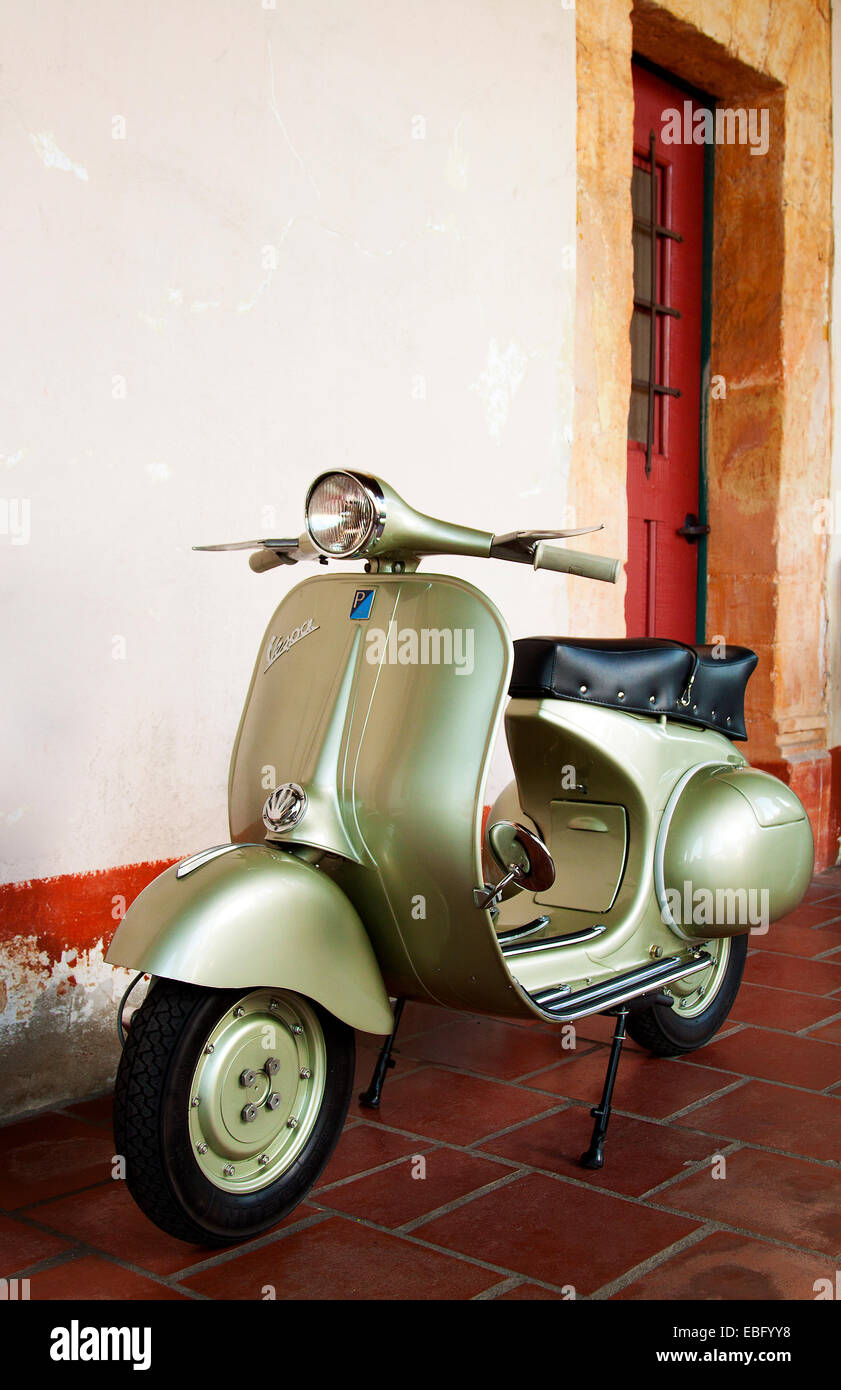 Jahrgang 1958-grüne Vespa-Roller vor einem rustikalen Gebäude Stockfoto