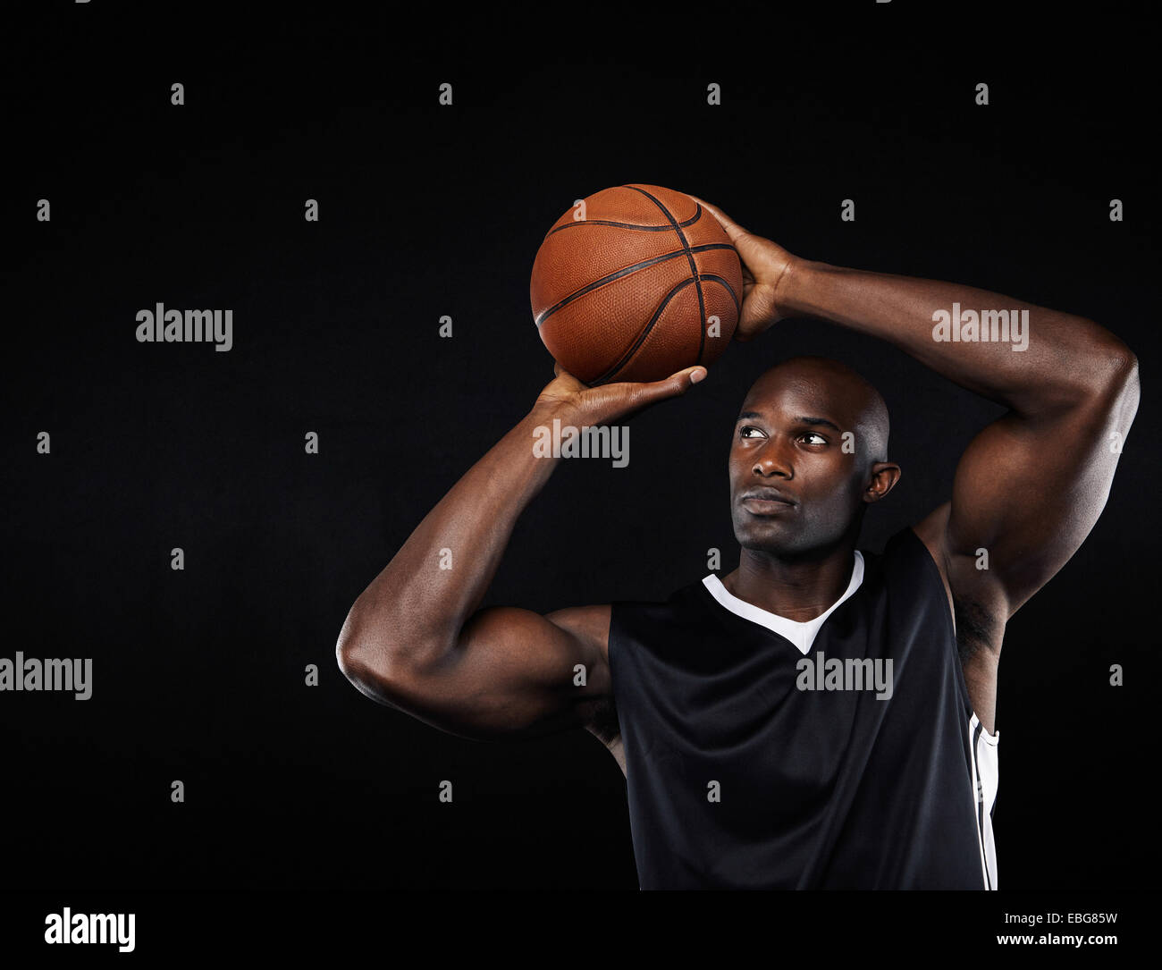 Young African American männliche Basketball-Spieler schießen auf den Reifen auf schwarzen Hintergrund Stockfoto