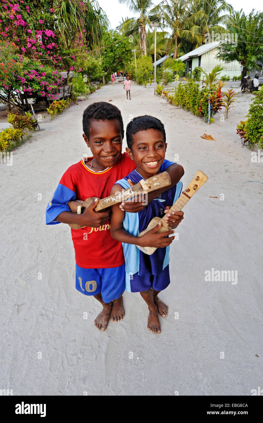 Zwei jungen mit Ukulele Spielzeug, Arborek, Raja Ampat, West-Papua, Indonesien Stockfoto