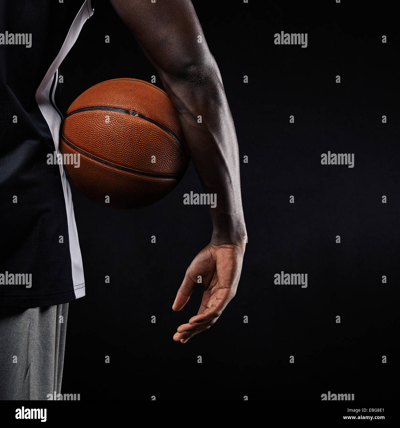 Nahaufnahme eines Basketballs in der Hand eines jungen afrikanischen Athleten vor schwarzem Hintergrund mit Textfreiraum. Stockfoto