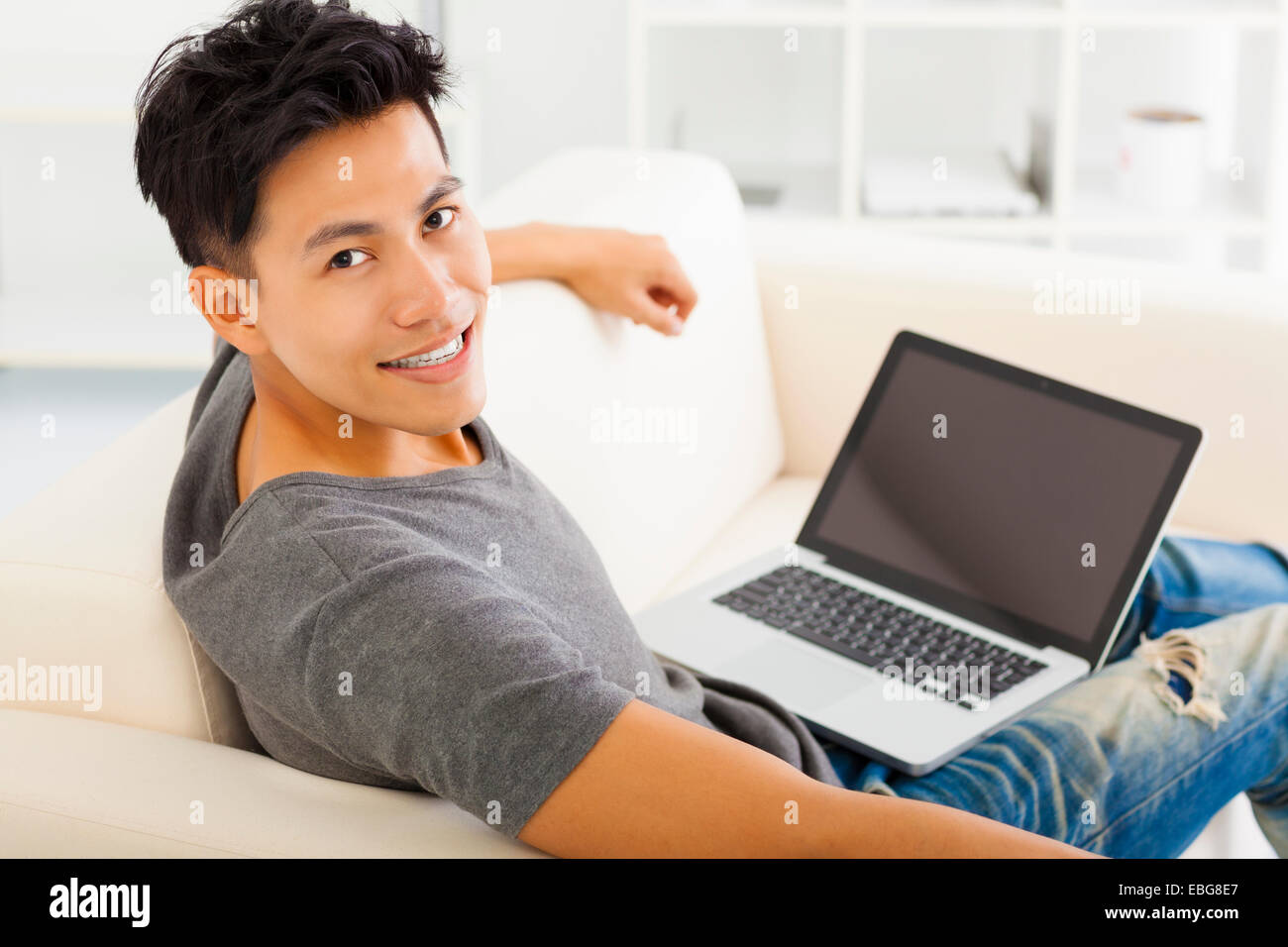 junge asiatische Mann sitzt im Sofa und Laptop verwenden Stockfoto