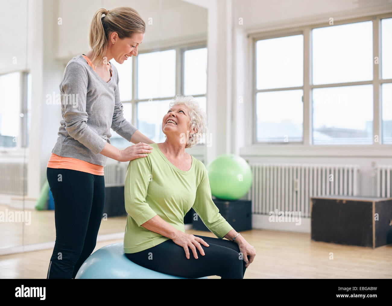 Weibliche Lehrer unterstützen ältere Frau im Health Club trainieren. Ältere Frau unterstützt von personal Trainer im Fitness-Studio. Stockfoto