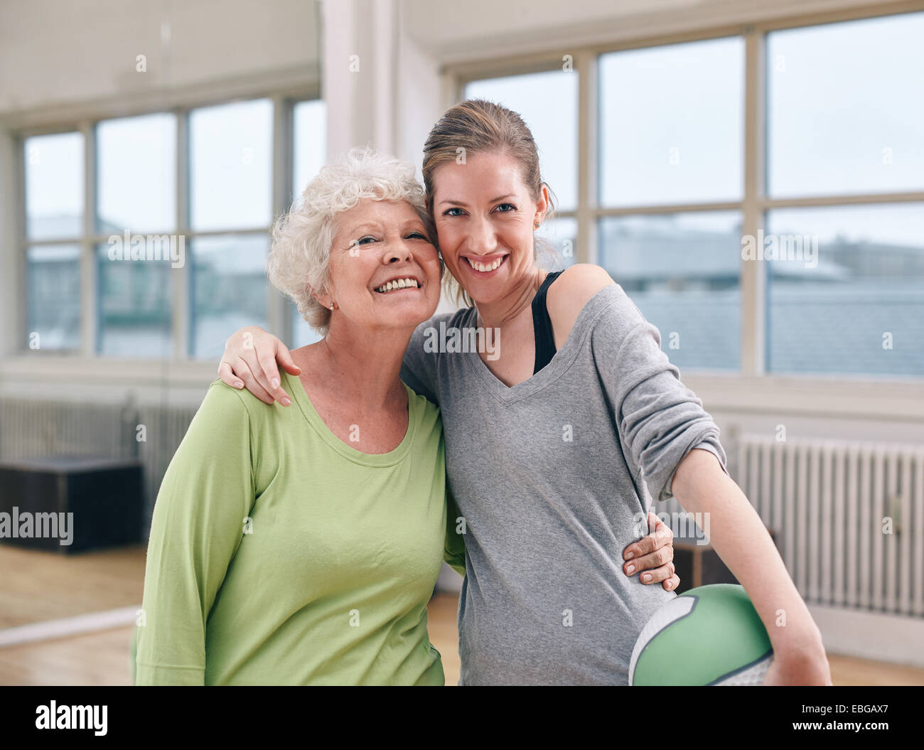 Porträt der fröhliche ältere Frau mit ihrem persönlichen Trainer im Fitness-Studio. Zwei Frauen stehen gemeinsam Lächeln in die Kamera im Health club Stockfoto