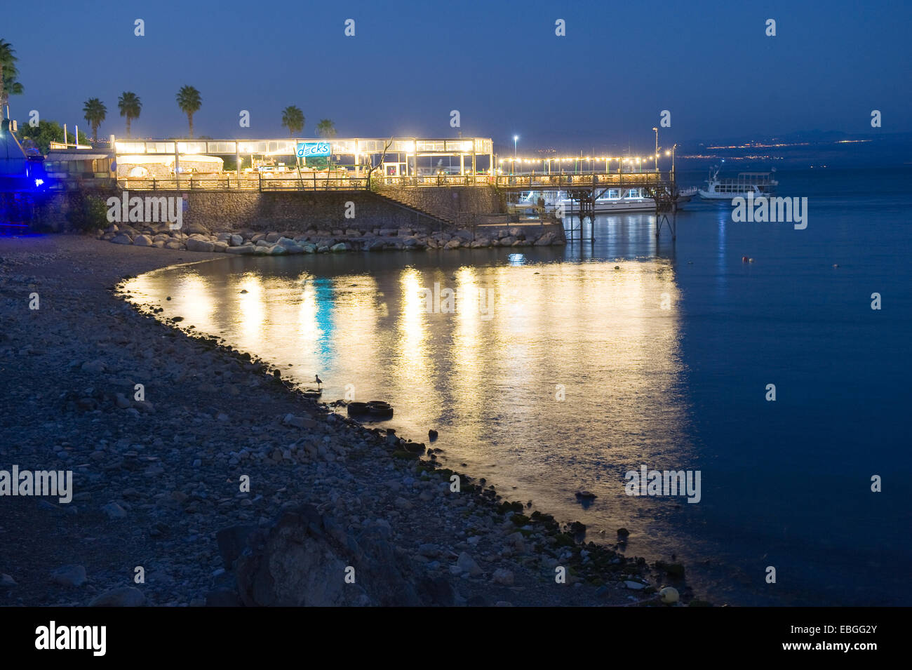 Ligths von einem Restaurant spiegeln sich im Wasser des Sees von Galiläa an der Küste von Tiberias Stockfoto