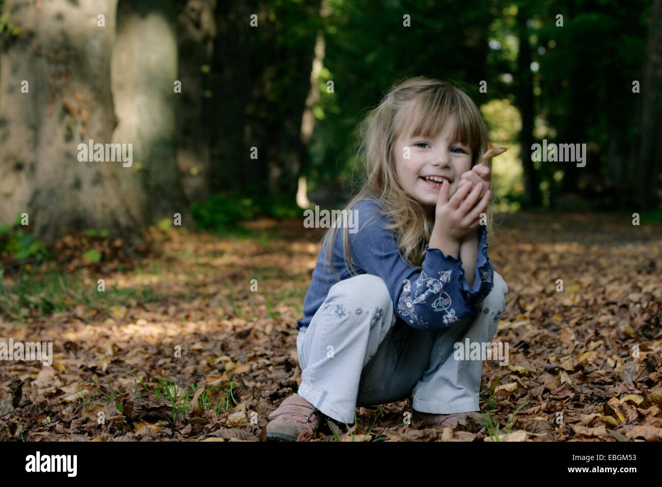 kleine Mädchen spielen mit Herbstlaub Stockfoto