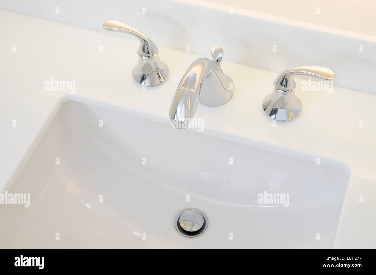 Waschbecken im Badezimmer und Zähler: Nahaufnahme eines Badezimmer Waschbecken, Chromhahn und weiße Theke. Stockfoto