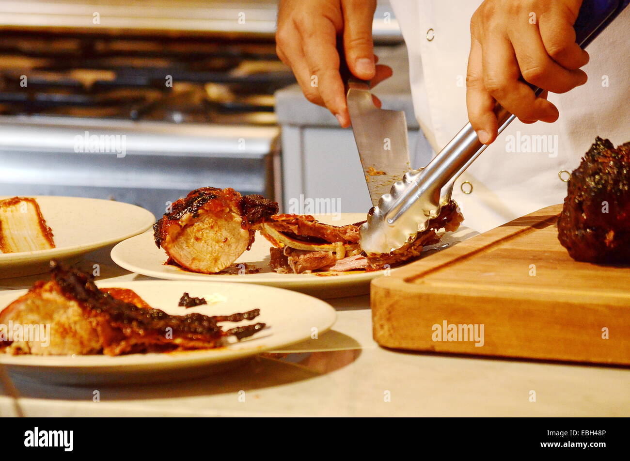 Kochs Hände schneiden und servieren Wildschwein Rippen Stockfoto