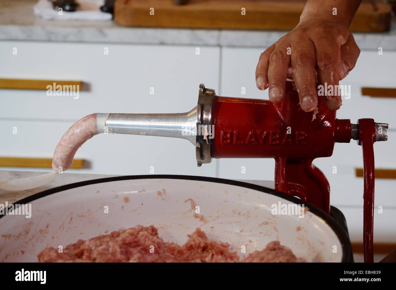 Kochs Hand mit Fleischwolf, um das Gehäuse um eine Wurst aus  Schweinefleisch zu füllen Stockfotografie - Alamy
