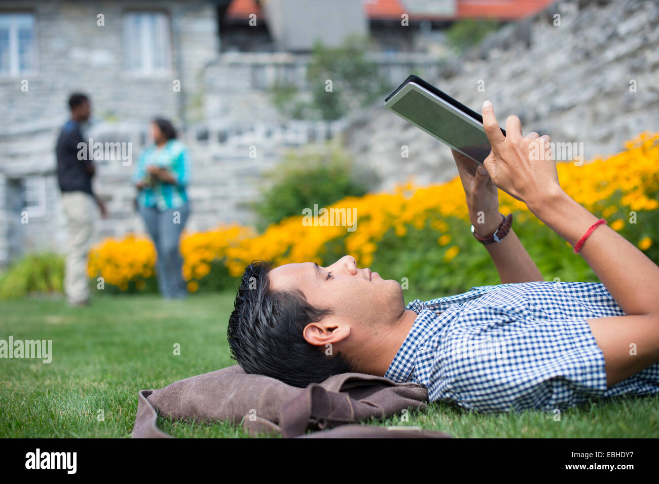 Männliche Schüler liegen auf dem Rasen mit digital-Tablette Stockfoto