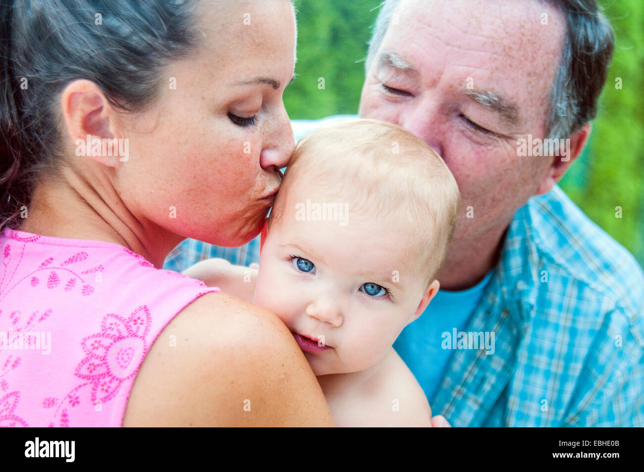Nahaufnahme von Mutter und Großvater küssen Babymädchen Stockfoto