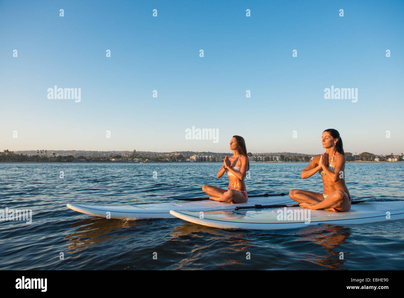 Zwei Frauen im Lotussitz auf Paddleboards, Mission Bay, San Diego, Kalifornien, USA Stockfoto