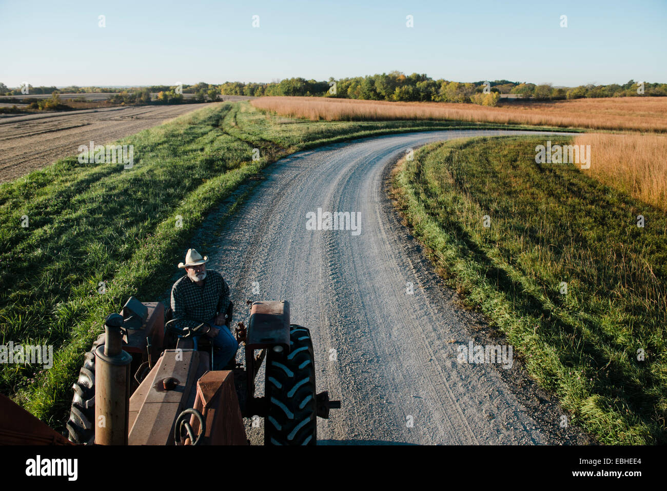 Erhöhte Ansicht der senior männlichen Bauer Traktor fahren auf der Landstraße, Plattsburg, Missouri, USA Stockfoto