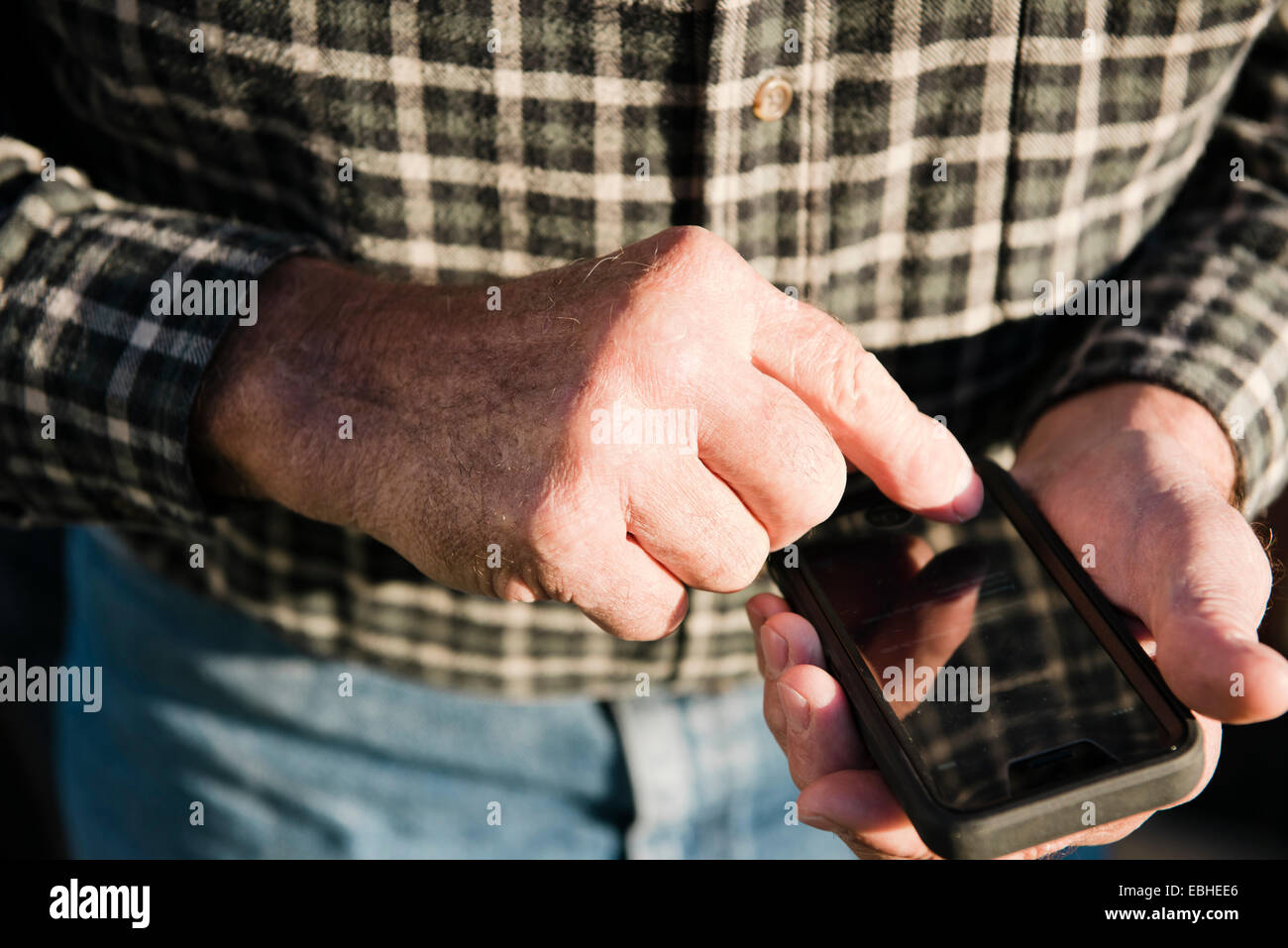 Nahaufnahme von senior männlichen Bauern mit Touchscreen auf Smartphone zugeschnitten Stockfoto