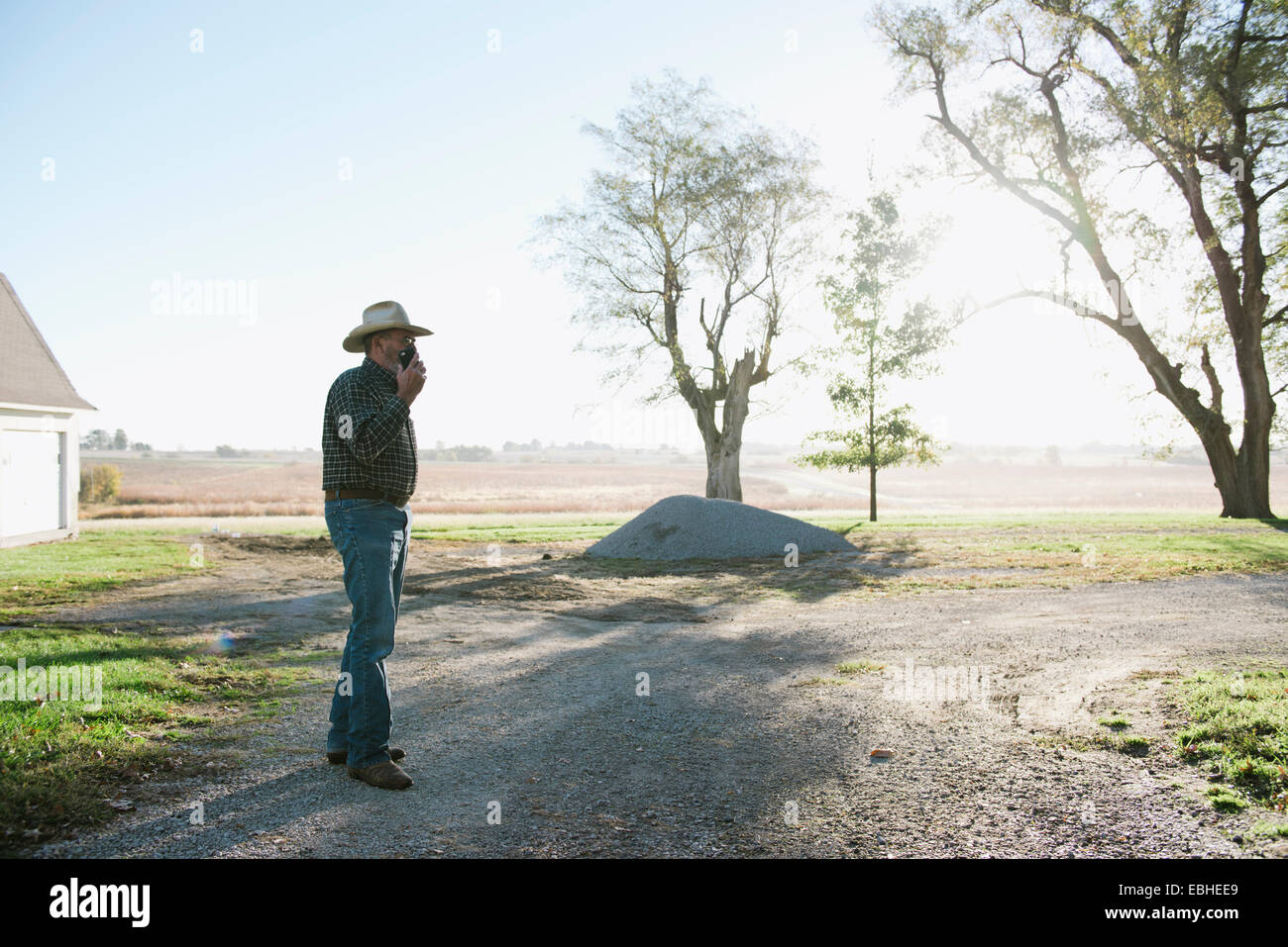 Senior männlichen Bauern im Chat auf Smartphone auf Feldweg, Plattsburg, Missouri, USA Stockfoto