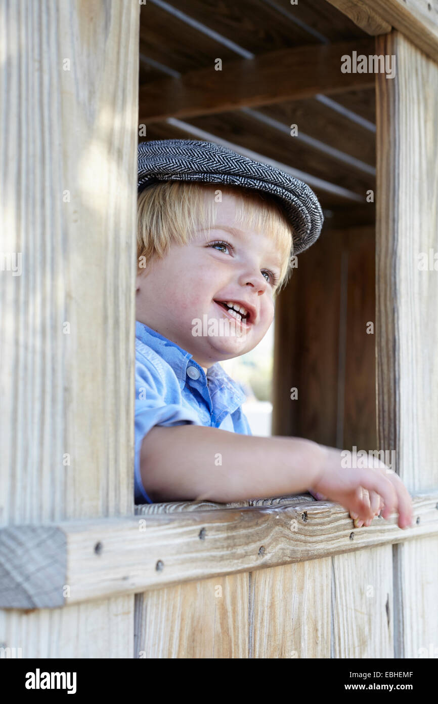 Männliche Kleinkind in flache Kappe aus Schuppen Fenster gelehnt Stockfoto