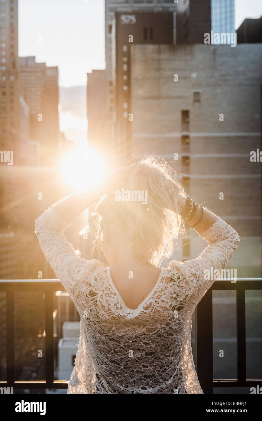 Junge Frau mit den Händen in die Haare im Sonnenlicht Stockfoto