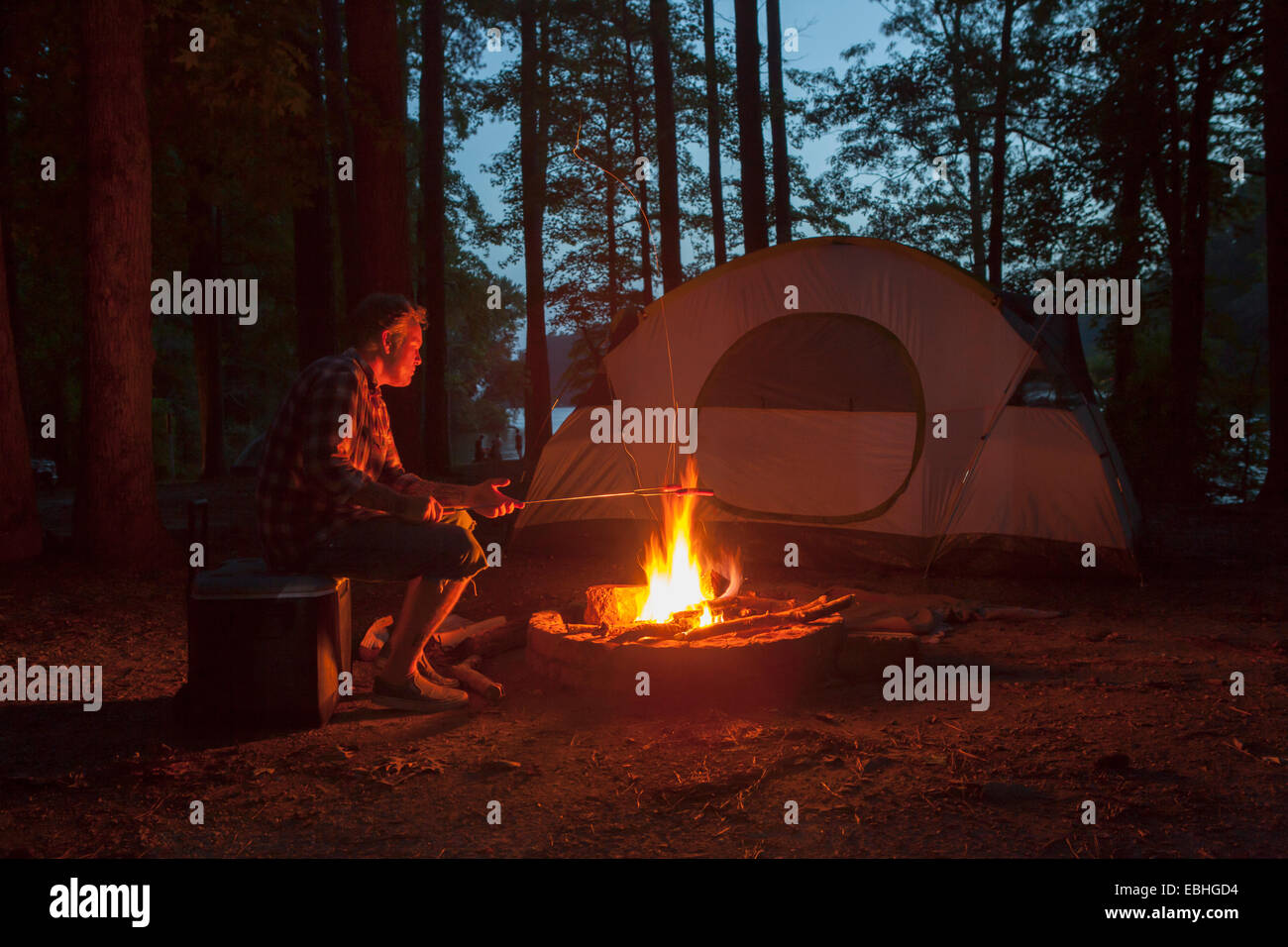 Mann, Kochen am Lagerfeuer im Wald bei Nacht, Arkansas, USA Stockfoto